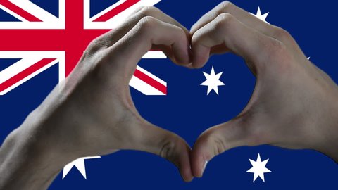 Man Hands make Heart Sign on Flag of Australia. Close Up.