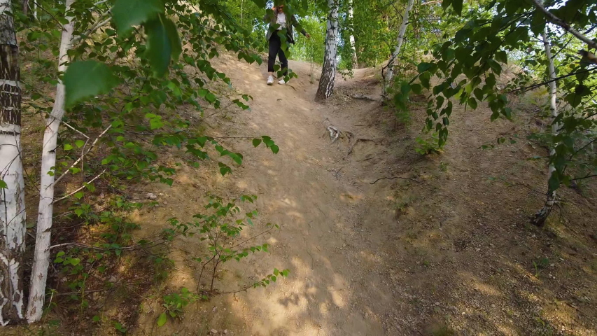 a girl walks along a forest road. left coniferous forest right birch grove, summer forest