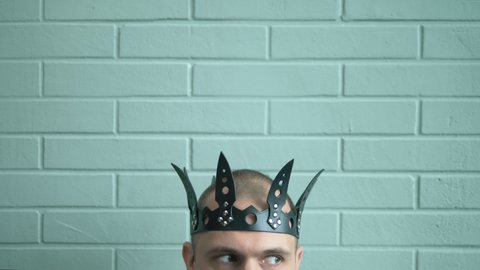 closeup. male head in a black leather crown on a brick wall background.