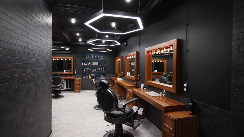 Vintage barbershop interior - movement along the chairs, wooden tables and mirrors. Stylish hair studio indoors. Stylish beauty salon design with modern lighting and lamps. | Shutterstock HD Video #1055208863