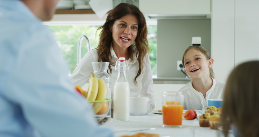 Authentic shot of a happy smiling family is enjoying their time together while having a breakfast in a kitchen at home in the morning. Royalty-Free Stock Footage #1055209310