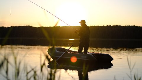 Fishing at sea, Fisherman in a boat, Fishing during sunset, Active rest. A man in a cap fishes fishing while standing in a boat at sunset