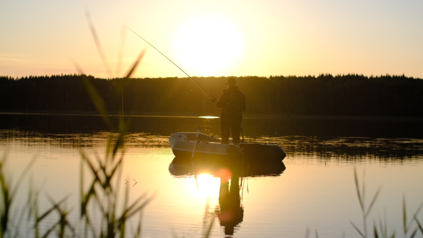 GO Everywhere.Fishing at sea, Fisherman in a boat, Fishing during sunset, Active rest. A man in a cap is fishing while standing in a boat during sunset. Sun flare