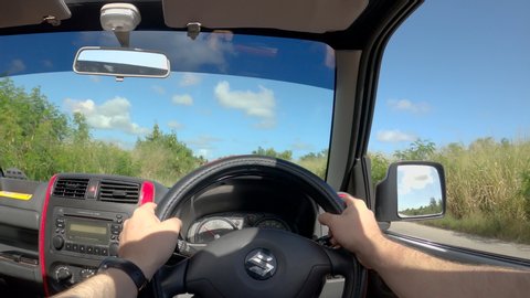 BRIDGETOWN, BARBADOS, CARIBBEAN ISLANDS, DECEMBER 2019: POV: Driving down a scenic suburban road in sunny Barbados in a red Suzuki jeep. Driving through the tranquil outskirts of sunny Bridgetown.