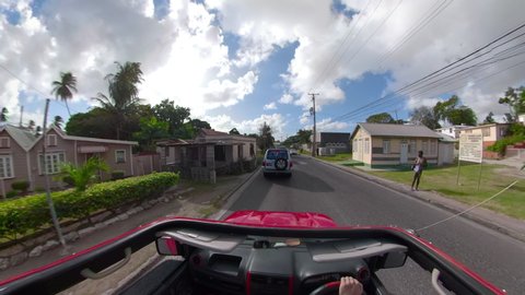 BRIDGETOWN, BARBADOS, CARIBBEAN ISLANDS, DECEMBER 2019: POV: Driving in old red Suzuki SUV around the scenic outskirts of Bridgetown on sunny summer day. Driving past locals and tourists in Barbados