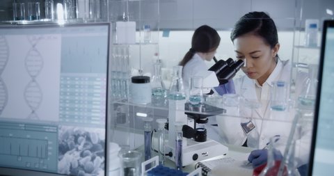 Multi ethnic, female team studying DNA mutations. Wearing protective workwear. Computer screens with DNA