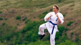 Fit young woman practicing her kickboxing outdoors in open countryside in a healthy active lifestyle concept
