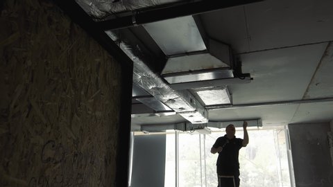 Silhouette of a craftsman who makes the installation of ventilation systems in the house. Finishing with ventilation networks of the new building.