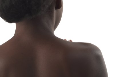 View from back of black young woman applying cream on her shoulder on white background