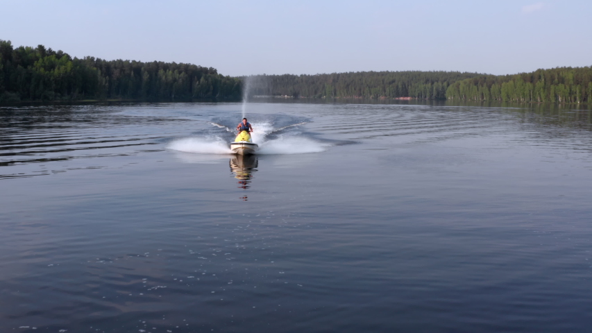 A young man is enjoying life while riding on a personal watercraft. The concept of relaxation and a healthy lifestyle. Aerial view Royalty-Free Stock Footage #1055223047