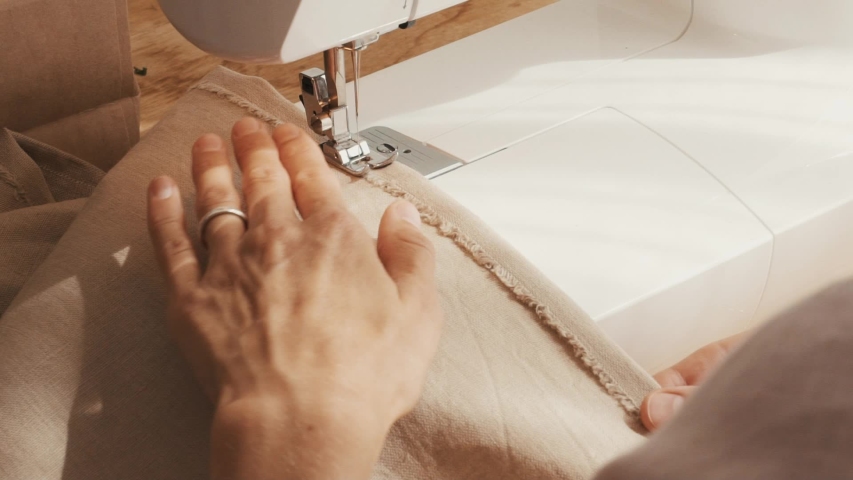 The process of creating from linen fabric in an electric sewing machine and sews the stitch along the edge into the bending with an open cut
Hand made linen, towel, tablecloth,  clothes, interior item | Shutterstock HD Video #1055223137
