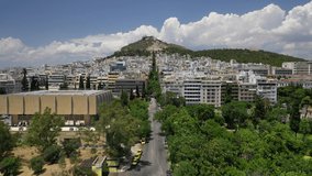 Aerial drone video of Athens urban dense populated cityscape leading to iconic Lycabettus hill and uphill church of Saint George, Attica, Greece