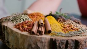 Woman rotates wooden tray with different kinds of spices. Turmeric falls on the heap to the round wood salver with variety of colorful spice. - Powered by Shutterstock - Get 15% off with code: PIKWIZARD15