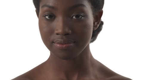 Close-up portrait of young black woman applying lipstick on her lips on white background