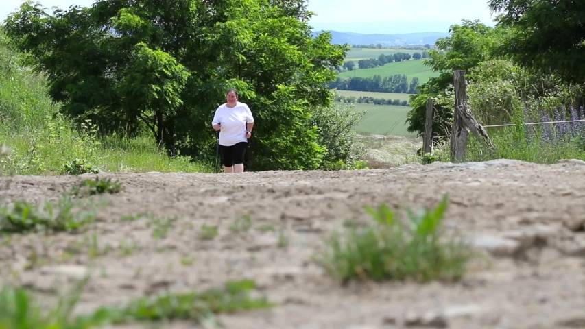 Overweight woman walking on hiking trail. Slimming and active lifestyle theme. 