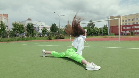 energetic young girl with long hair in tracksuit dancing dancehall twerk, street modern dance, shakes her buttocks in the open air. Booty Dance. Gimbal shot