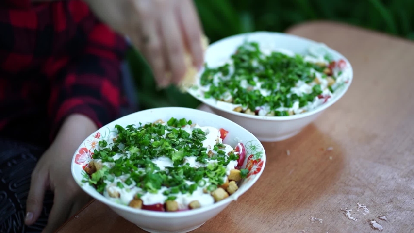 Woman prepares salad outdoors. Close-up of women