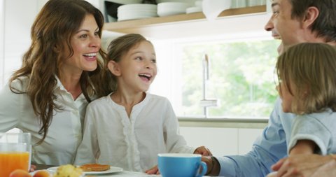 Authentic shot of a happy smiling family is enjoying their time together while having a breakfast in a kitchen at home in the morning.