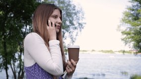 girl with coffee to go talking on smartphone in park