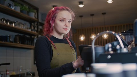 A young Barista Girl Makes delicious coffee. Coffee shop worker with a modern hairstyle, Fashionable Barista, Modern gir
