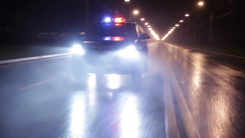 Three police cars in high speed pursuit. Emergency response police patrol vehicle speeding to scene of crime at night and rain. Outdoor front view of police traffic auto driving. Royalty-Free Stock Footage #1055240063