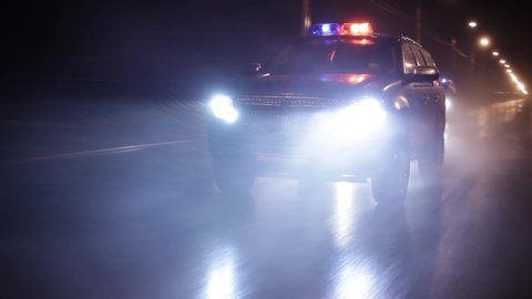 Three police cars in high speed pursuit. Emergency response police patrol vehicle speeding to scene of crime at night and rain. Outdoor front view of police traffic auto driving.