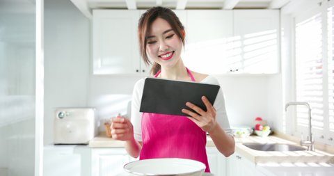 Asian prettey housewife use tablet to look for the cooking recipe on internet