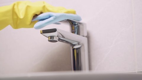 Close-up of a hand in rubber glove washes faucet in the bathroom. Without a face