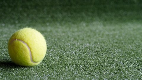 Close up tennis ball and white golf ball on green grass in motion. Golf and Tennis sports background with copy space.