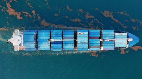 Top down 4K drone footage of water transportation. Aerial view of large container ship in Atlantic ocean. Big blue vessel stocked with cargo containers exporting goods. Massive freight shipment by sea