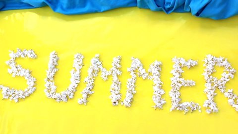 The inscription Summer is written in white flowers of lilac on a yellow background. The word Summer is written with lilac flowers. Flower inscription Summer. Background for a greeting card. Wedding