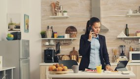 Freelancer late at work while eating breakfast in a hurry. Concentrated business woman in the morning multitasking in the kitchen before going to the office, stressful way of life, career and goals to