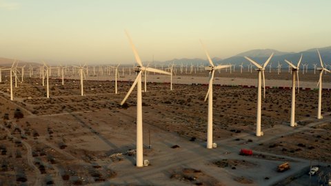 Cinematic aerial of field with windmills at sunset, desert in California, renewable energy