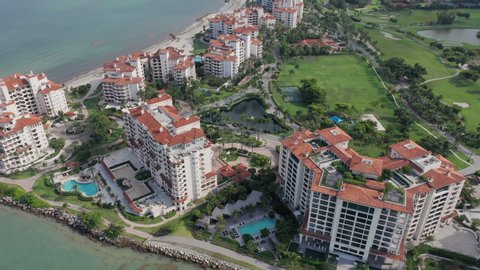 4K aerial view of the prestige residential homes and apartments on the Fisher Island, in Miami suburban area, Florida state. Exclusive real estate with the ocean view. Front line buildings with pools