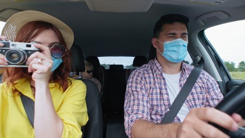 cheerful spouses man and woman in medical masks with male child in car seat are inherited by family trip together by car during summer holidays
