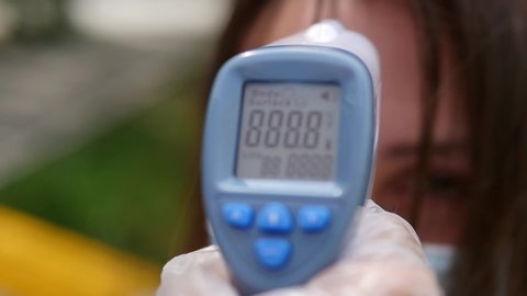 A nurse measures a patient’s temperature using a non-contact infrared thermometer.