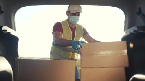 delivery pandemic covid coronavirus vaccine a goods and food product. man volunteer works stacks boxes in a car. parcel delivery concept. lifestyle courier driver in gloves loads boxes during