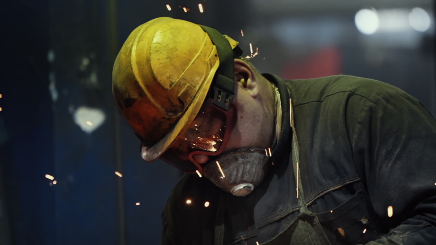 Tough Work of a Welder in Green Uniform and Protection Yellow Helmet at Steel Making Factory. Angle grinder at Metal Production. Sparks, Slow Motion, Close Up | Shutterstock HD Video #1055265140