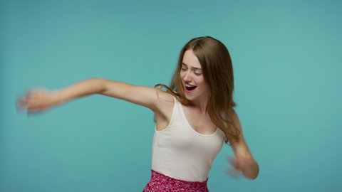 Amazing beautiful playful girl moving in dance, smiling carefree and stops in dab dance pose, performing dabbing trends, gesture of success, internet meme. studio shot isolated on blue background