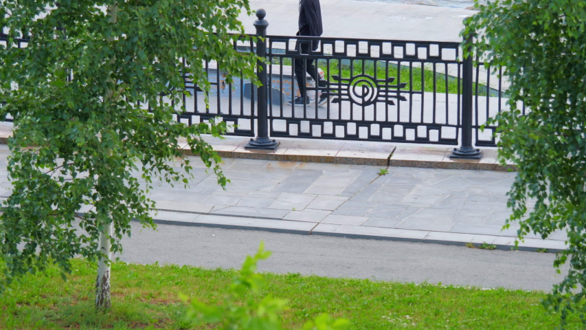 Teenage girl in bright clothes riding a skateboard in a city park. The concept of urban life and youth culture