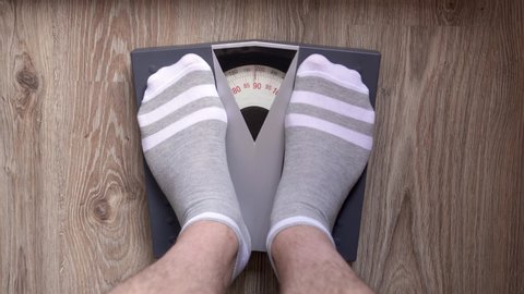 Man steps on the mechanical floor  scales for checks his weight. The concept of tackling overweight and obesity.