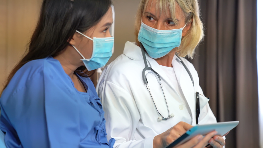 Female doctor giving a consultation to a patient at on bed with tablet and explaining medical informations and diagnosis. Royalty-Free Stock Footage #1055277032