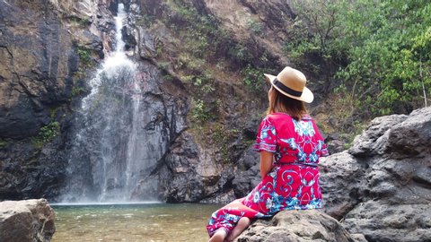 Asian woman in colorful dress enjoying deep forest & famous Jokkadin Waterfall in Thailand