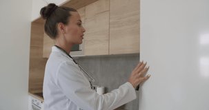 Lunch break in a medical facility. A young woman doctor taking out a lunch box from the refrigerator, rubbing his hands with an antiseptic and biting an apple. 4k raw video footage slow motion