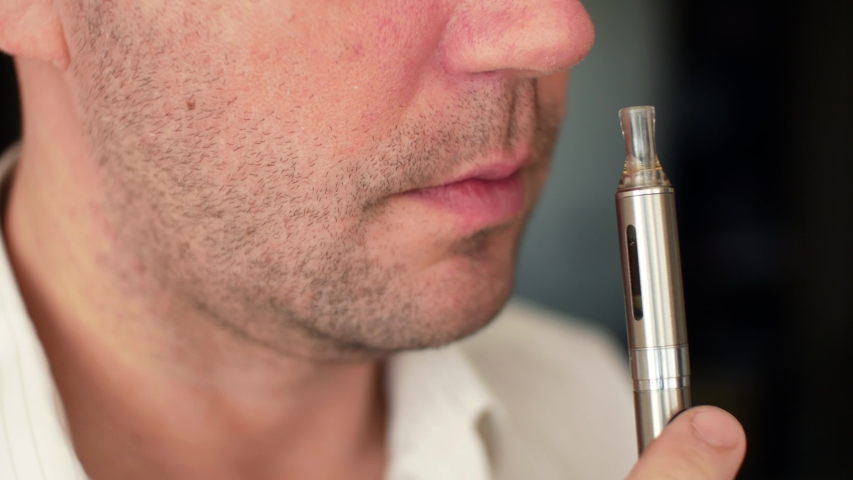 Vaping smoking electronic cigarettes. A man inhales vapor of an vape electronic cigarette with synthetic nicotine  Royalty-Free Stock Footage #1055288837