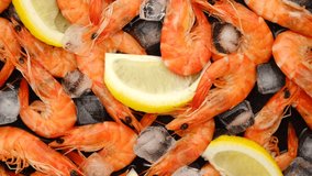 rotating shrimps with lemon and ice cubes  closeup. top view