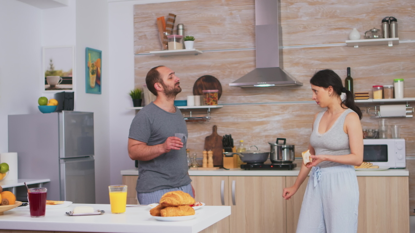 Cheerful couple dancing in kitchen and having fun during breakfast. Carefree husband and wife laughing, singing, dancing listening musing, living happy and worry free. Positive people Royalty-Free Stock Footage #1055298593