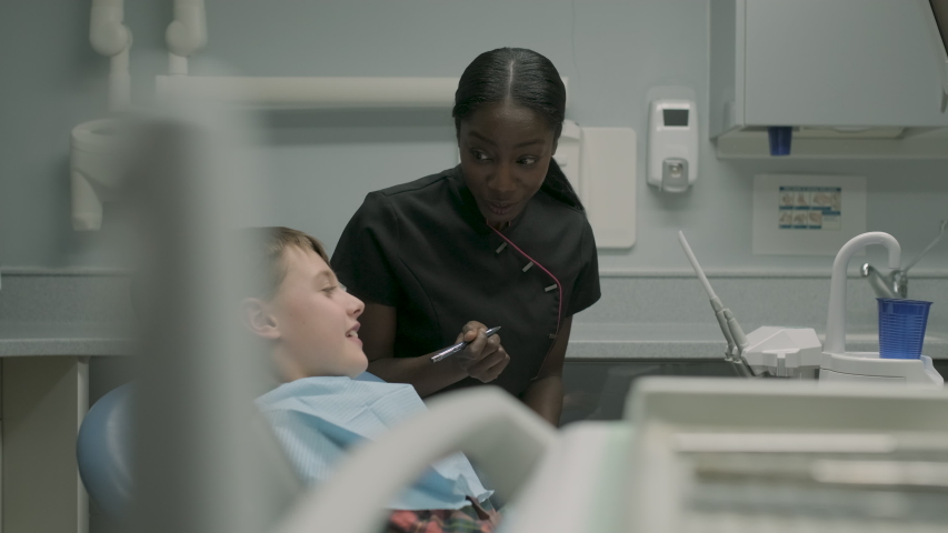Dental assistant speaking with boy sitting on dental chair, a Healthcare Video by TunedIn by Westend61
