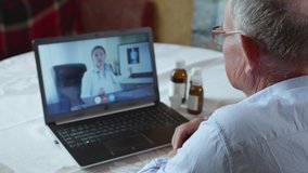patient care, elderly old man consults with his doctor via video communication using modern technologies sitting at laptop at table with medicines, medicine online