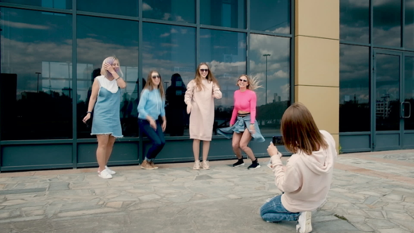 beautiful girls bounce up. Five girlfriends on a smartphone near glass windows. young people . walks in the spring. 20-25 years. The concept of the meeting. carefree weekend